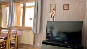 Een gezellige woonkamer met een televisie, houten meubels, een radiator en een raam met gordijnen.