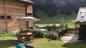 Een houten vakantiehuisje met een terras, compleet met een tafel, stoelen en een parasol.