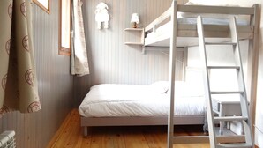 Een stapelbed met een ladder, een nachtkastje met een lamp en een wandplank.