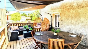 An outdoor patio with a round wooden table, two chairs, a hanging chair, and a cushioned sofa. - L'échappée Huroise, private pool and spa (Hure)