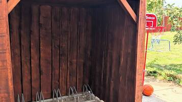 Eine Holzhütte mit Wellblechdach, einem Metallgestell und einem Basketballkorb.