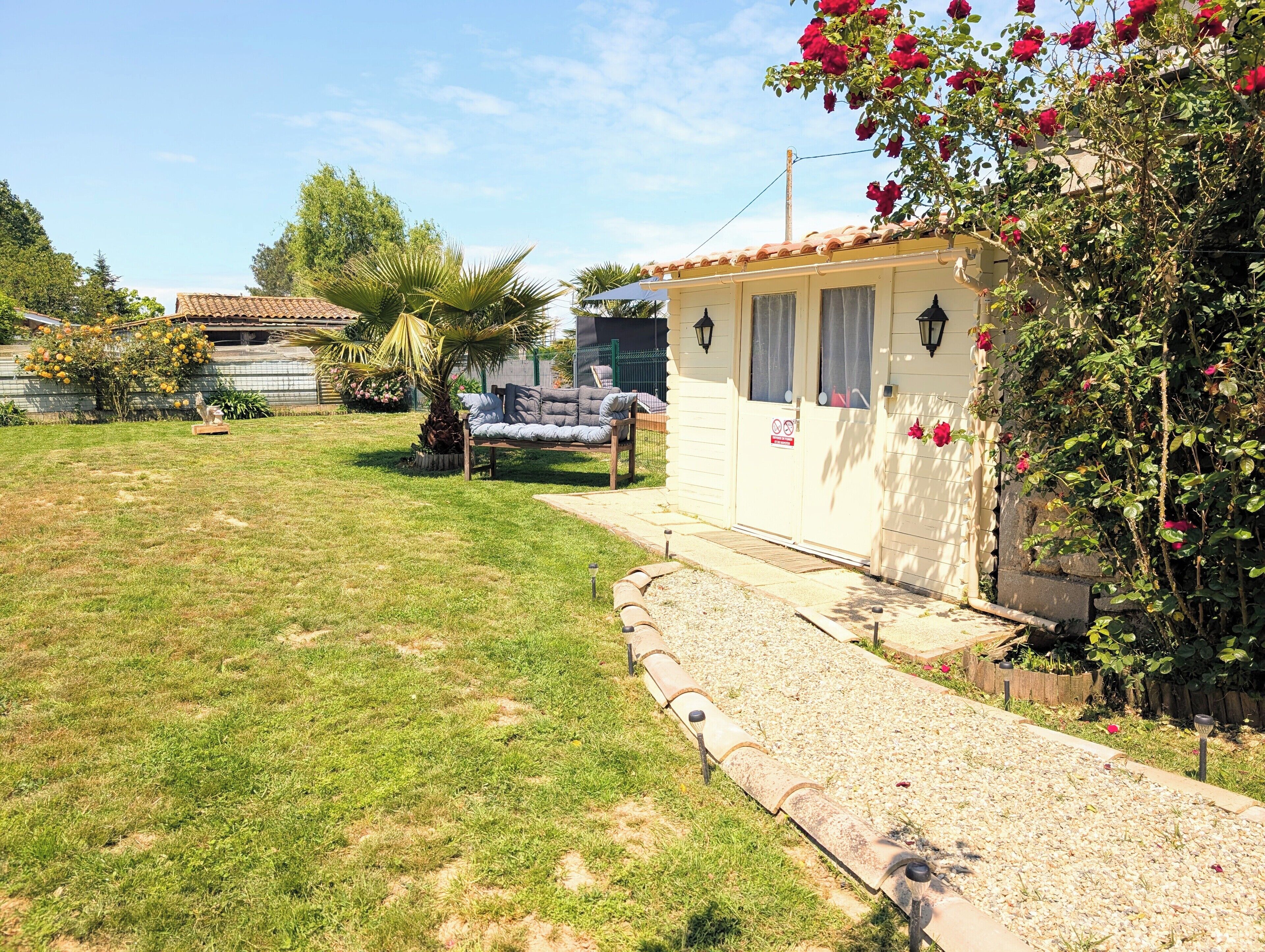 A small house with a garden, a patio, and a pathway leading to the entrance.