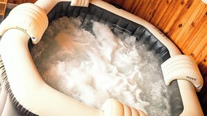 A hot tub in a wooden cabin with a wooden ceiling and walls, a wooden bench, and a sign indicating a 4-person maximum. - L'échappée Huroise, private pool and spa (Hure)