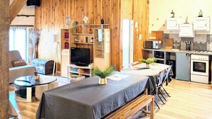 A rustic interior with exposed wooden beams, a dining area with a bench, a kitchen with modern appliances, and a television in the living area. - L'échappée Huroise, private pool and spa (Hure)