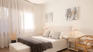 Ein Schlafzimmer mit einem Bett, Nachttischen, einem Sessel und Bildern an der Wand.