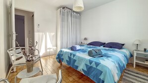 Une chambre à coucher avec un lit, une chaise, une petite table et une table de chevet.