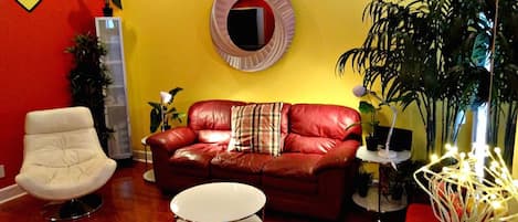 A living room with a red leather sofa, a white armchair, and a small round table.