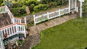 A serene garden with a pond, a wooden deck, and a white picket fence.