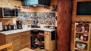 A compact kitchen with a built-in oven, coffee maker, and a stone backsplash.