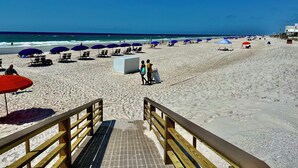 A beach with a wooden boardwalk leading to the shore, featuring sun umbrellas and beach chairs. - 17th Floor East Corner Unit with 2 Balconies, Huge Beachfront Pool, Low Host Fee (Gulf Shores)