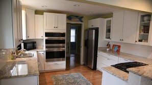 A kitchen with white cabinets, a microwave, an oven, a refrigerator, and a gas stove.