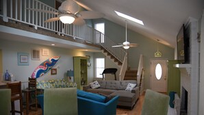 A spacious living room with a staircase, a fireplace, and a ceiling fan.