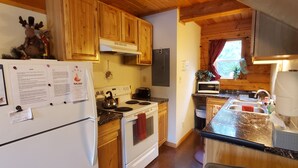 A compact kitchen with wooden cabinets, a stove, a microwave, and a refrigerator. - Alaska Aurora Adventures  Cabin B<br>World class Northern lights viewing (North Pole)