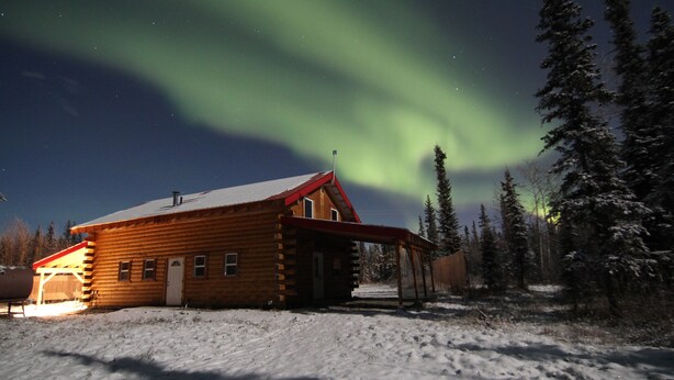A log cabin with a snow-covered ground and a view of the northern lights. - Alaska Aurora Adventures  Cabin B<br>World class Northern lights viewing (North Pole)