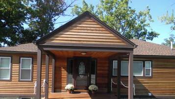 A two-story wooden house with a front porch and a small front yard.