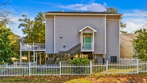 A two-story house with a front porch, a staircase leading to the second floor, and a white picket fence.