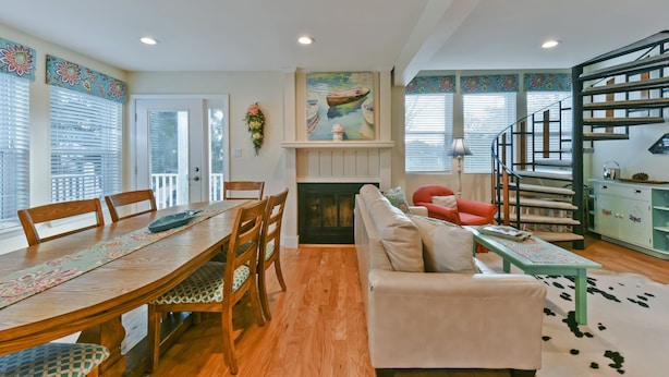 A spacious living area with a dining table, sofa, and staircase.