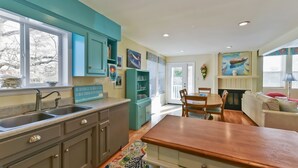 A kitchen with teal cabinets, a wooden dining table, and a view of the outdoors.