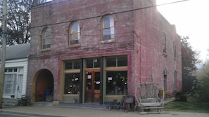 A two-story brick building with large windows and a wooden bench outside. - Downtown historic main street (Ste. Genevieve)