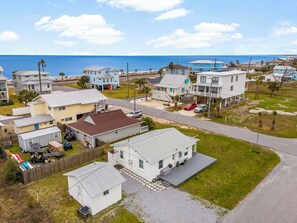 A coastal residential area with houses, a clear view of the ocean, and a paved road. - Sweet Cozy Cottage - Gulf of AMERICA View (Mexico Beach)