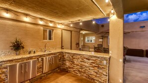 A kitchen with a granite countertop, stainless steel cabinets, and a stone backsplash.