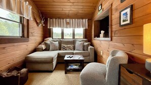 Interior d'una cabana acollidora amb un sofà modular, una taula petita i una cadira.