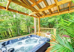 A hot tub in a wooden deck surrounded by lush greenery.