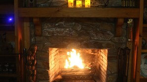 A fireplace with a TV above it, surrounded by wooden shelves and a stone wall.