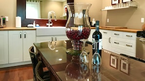 A modern kitchen with a glass-top table, a wine bottle, and a vase with red grapes. - Stunning contemporary North Shore Bungalow with hot tub. Steps to everything.  (Chattanooga)