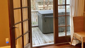 An open door leading to a wooden deck with a hot tub and a wicker chair. - Stunning contemporary North Shore Bungalow with hot tub. Steps to everything.  (Chattanooga)