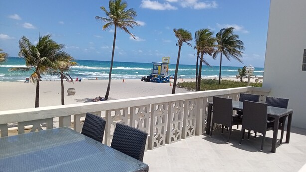 A balcony with a view of the beach, palm trees, and ocean waves. -  Gorgeous 360° Oceanfrnt Views* In the heart Famous Broadwlk*$Free Off St Park$* (Hollywood)