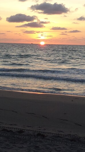 A beach with waves and a sunset.