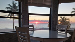 A round table with four chairs, large windows with a view of the sunset over the ocean, and palm trees. -  Gorgeous 360° Oceanfrnt Views* In the heart Famous Broadwlk*$Free Off St Park$* (Hollywood)