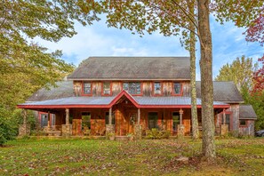 Een houten chalet met een rood dak, een stenen fundering en een veranda met buitenmeubels.