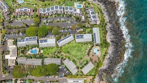 An aerial view of a coastal hotel with multiple buildings, parking areas, and a beach.