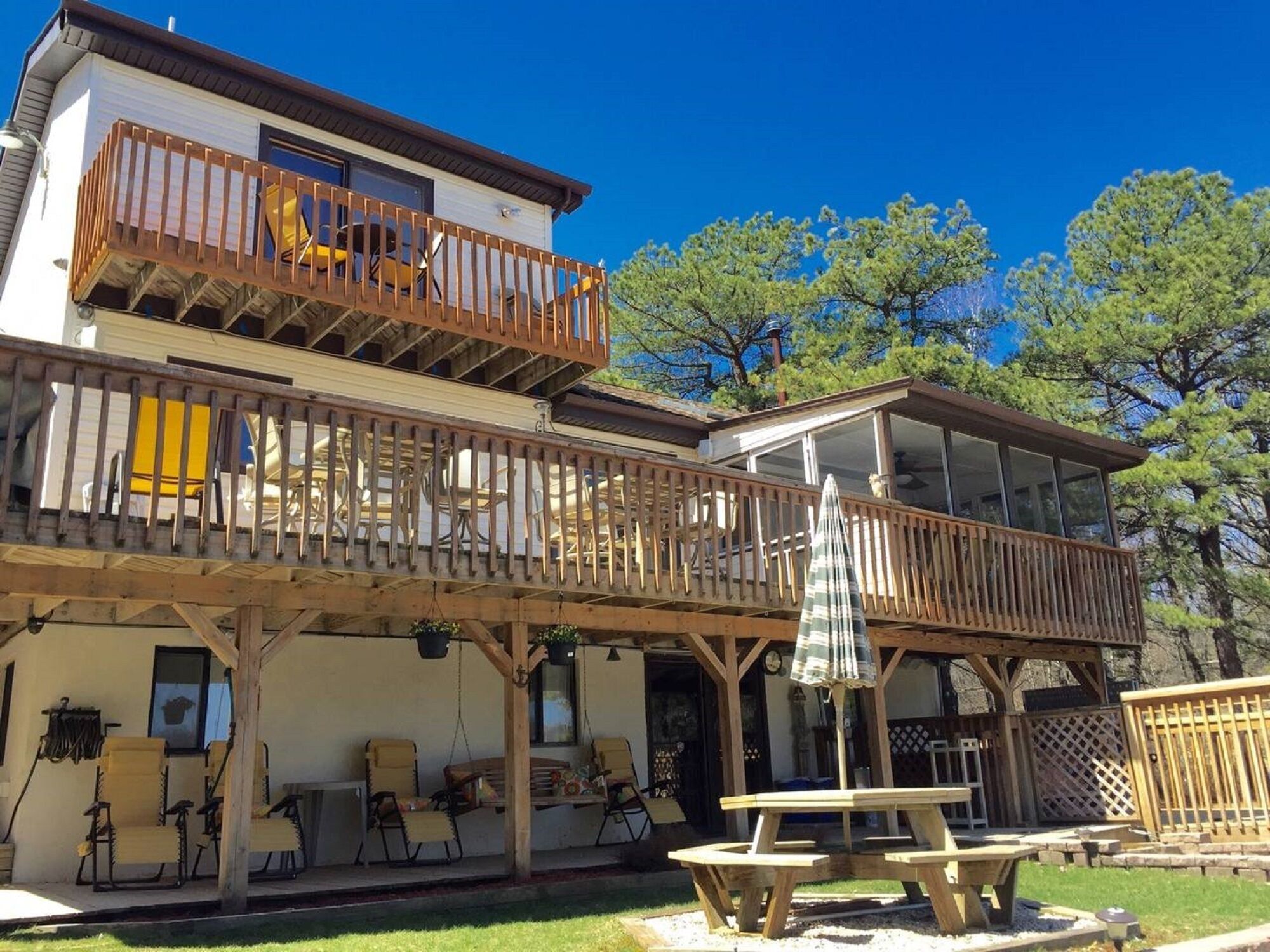 A two-story building with a wooden balcony, outdoor seating, and a covered patio area.