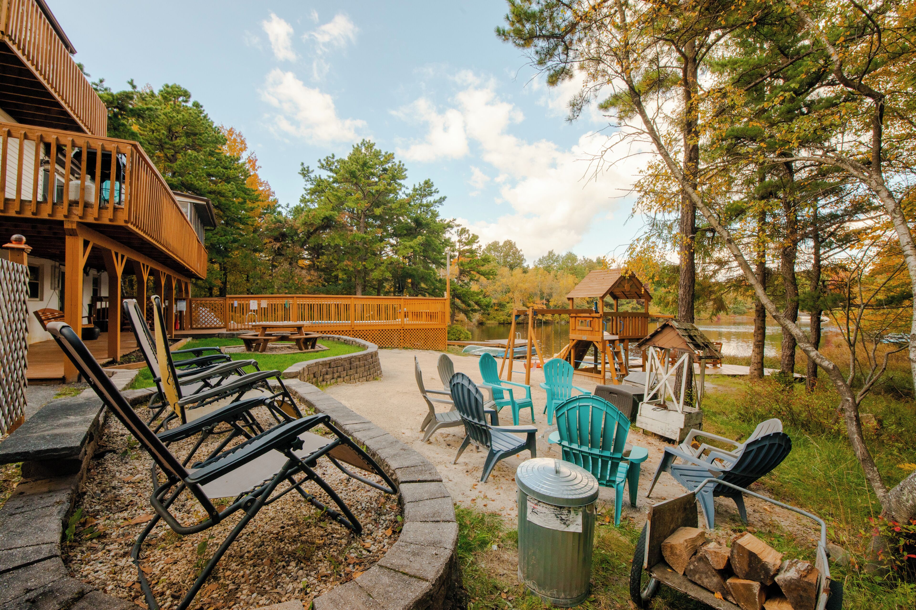 Eine Holzterrasse mit Sitzgelegenheiten im Freien, einer Schaukel und einer kleinen Holzkonstruktion.