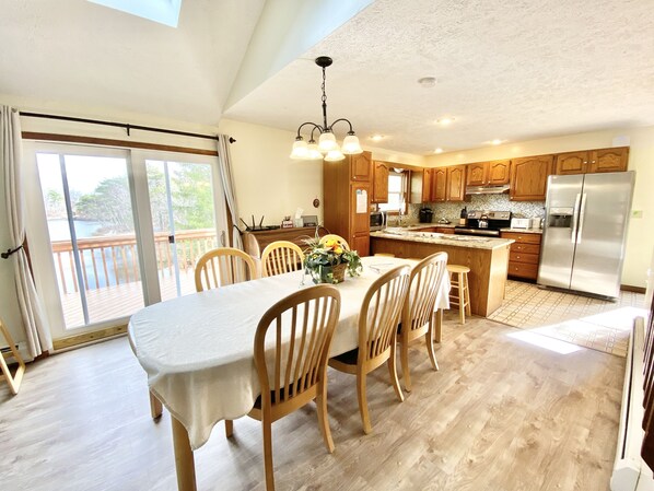 Una cocina amplia con armarios de madera, un refrigerador de acero inoxidable y una zona de comedor con mesa y sillas.