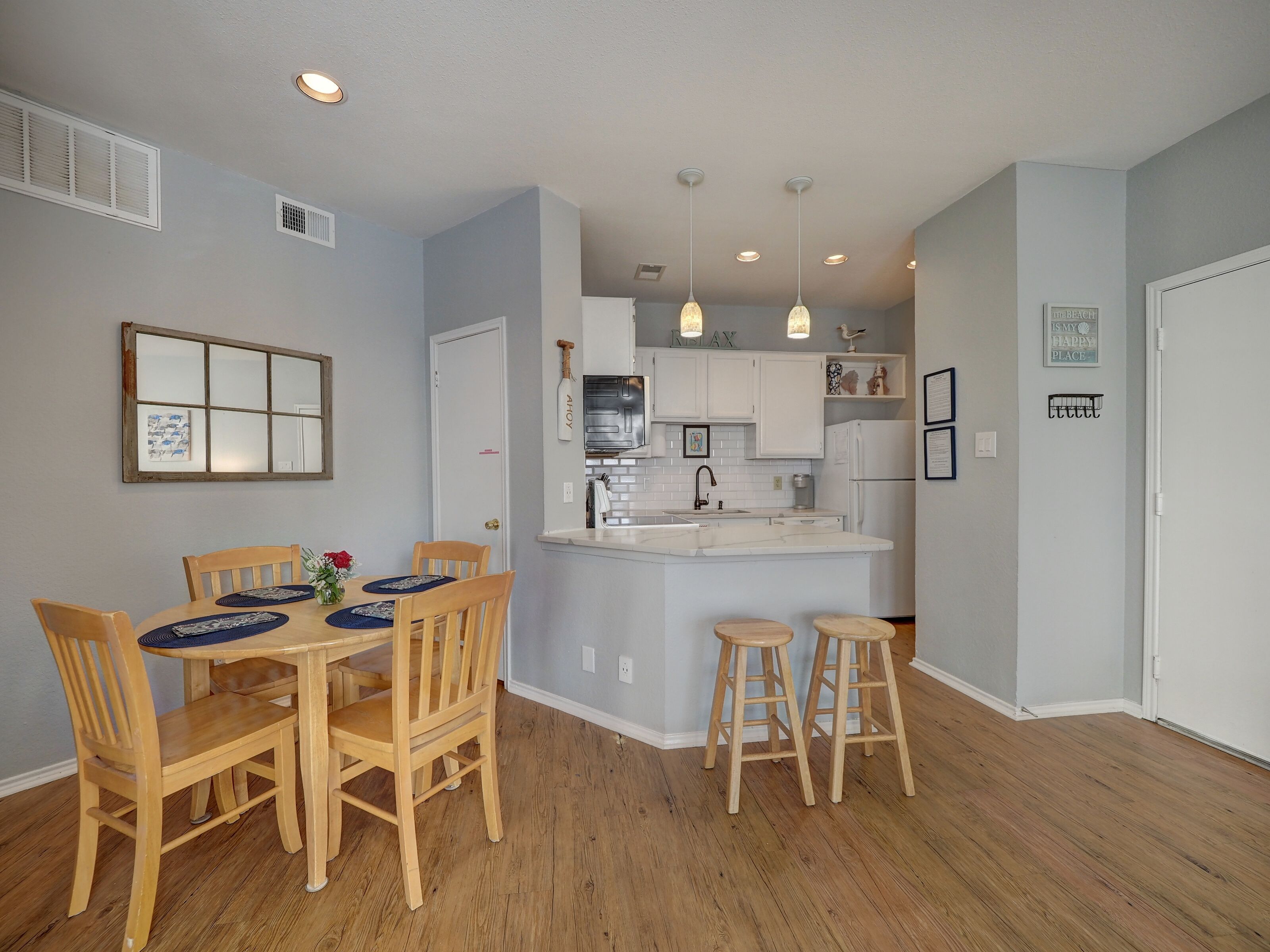 A modern kitchen with white cabinets, a central island, and pendant lighting.