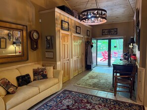 A cozy living room with a sofa, a patterned rug, and a chandelier. - Thunderbird Lodge: Sandy Beach, Pontoon Boats & Northwoods Memories (Lac du Flambeau)