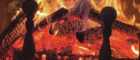 A fireplace with logs and a screen.