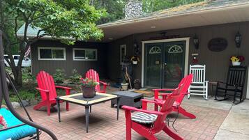 Une terrasse avec des fauteuils Adirondack rouges, une table et un pot de fleurs.