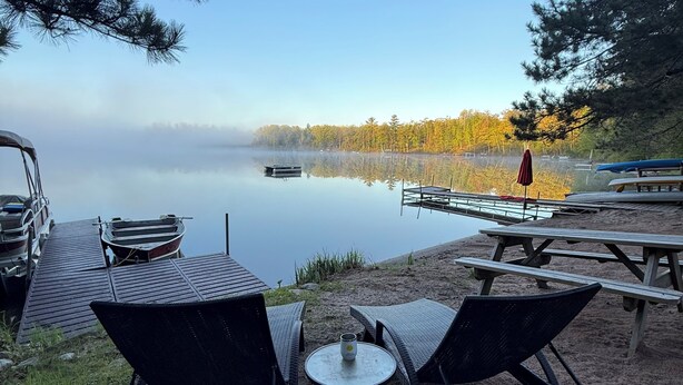 Una terrazza sul lago con sedie a sdraio, un tavolino e tavoli da picnic.