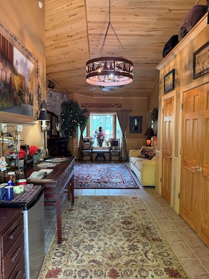 A wooden interior with a dining area, a chandelier, and a view through a window. - Thunderbird Lodge: Sandy Beach, Pontoon Boats & Northwoods Memories (Lac du Flambeau)
