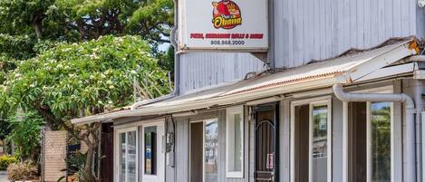 Un restaurant doté d’une terrasse et d’une enseigne publicitaire annonçant des pizzas, des beignets à la cannelle et d’autres spécialités.