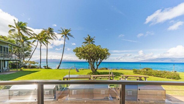 Una propiedad frente a la playa con un patio, palmeras y vistas al océano.