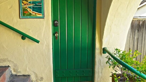 A green door with a doormat reading "Manzanilla College." - Cozy Studio Apartment with European style (Laguna Beach)
