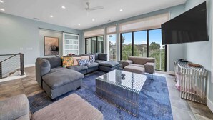 A modern living room with a sectional sofa, a glass coffee table, and a large TV.