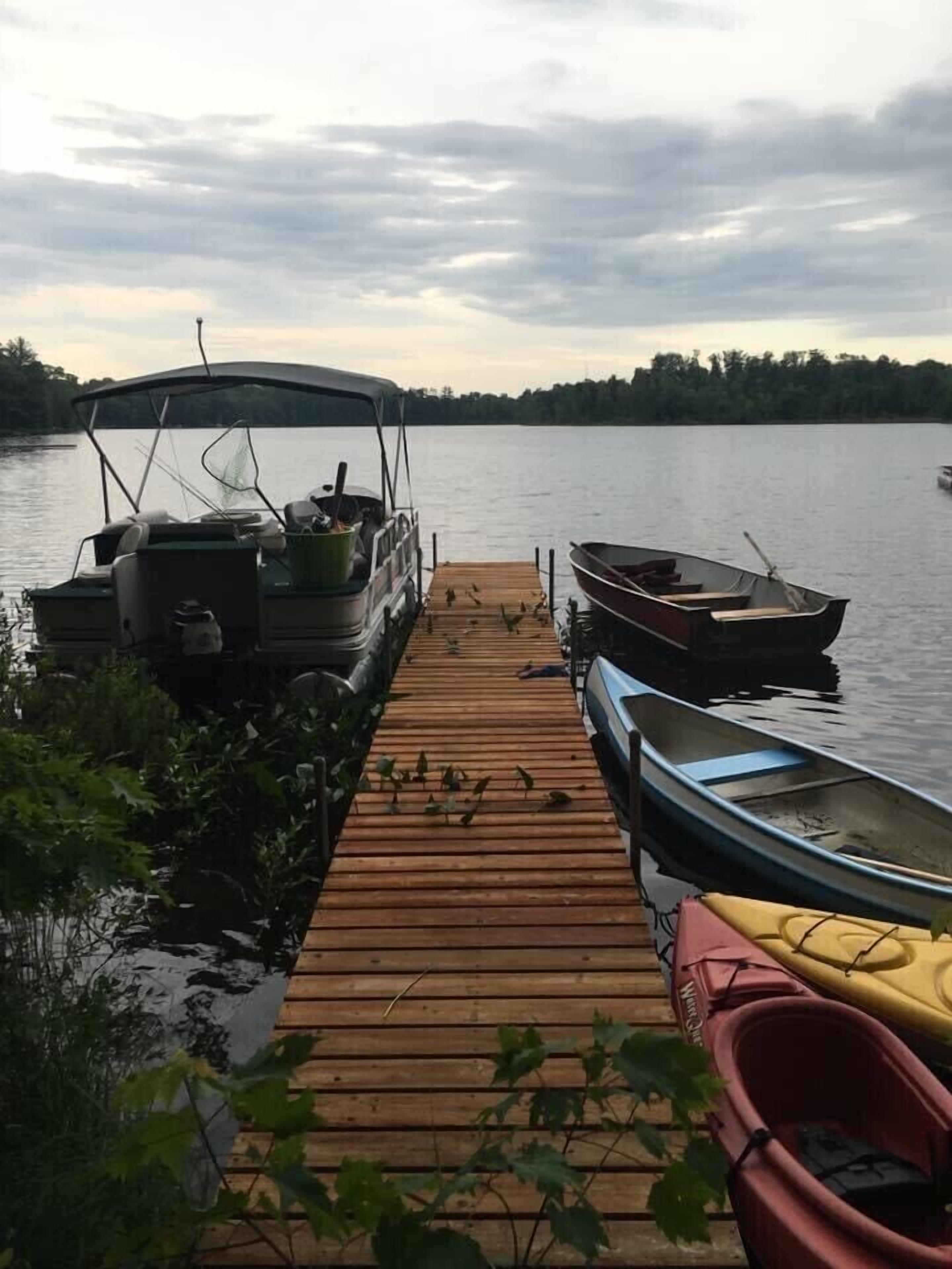 A wooden dock with a rowboat and a canoe docked at the end.