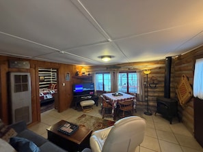 L'intérieur d'une cabane comprenant une télévision, une table à manger et une cheminée.